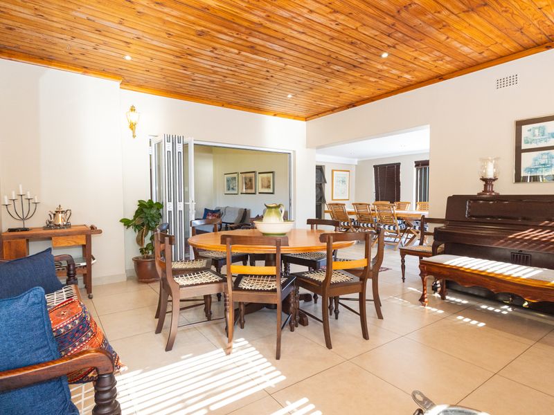 Spacious open-plan living and dining area featuring a warm timber tongue and groove ceiling, ceramic tiled flooring, and bi-fold doors leading to an adjacent room.