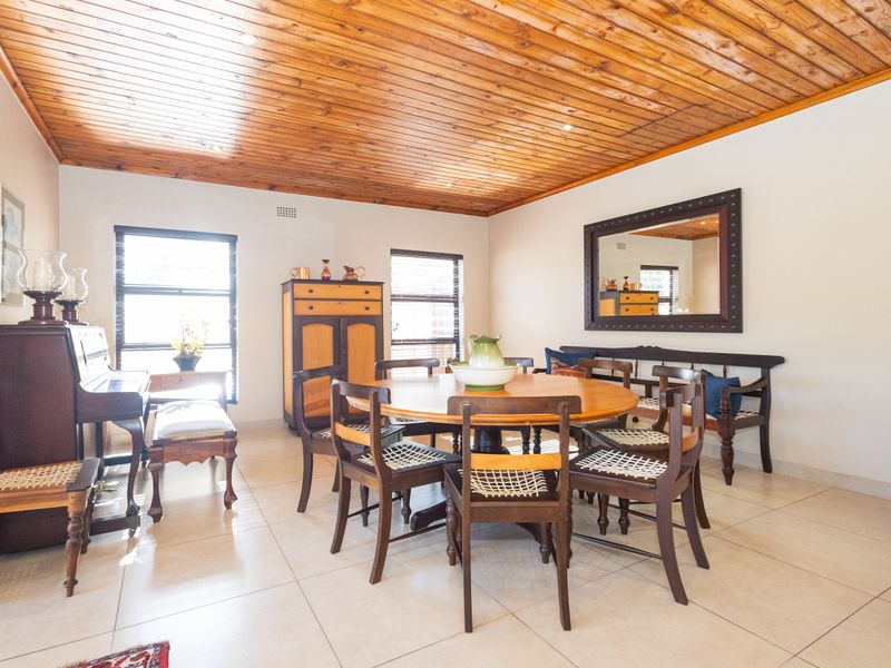 Spacious dining room featuring a warm timber tongue and groove ceiling, neutral tiled flooring, and large windows providing ample natural light.