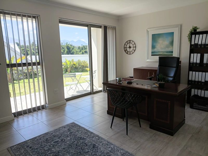 A bright office space featuring tiled flooring and large sliding glass doors that provide natural light and direct access to the outdoor area.
