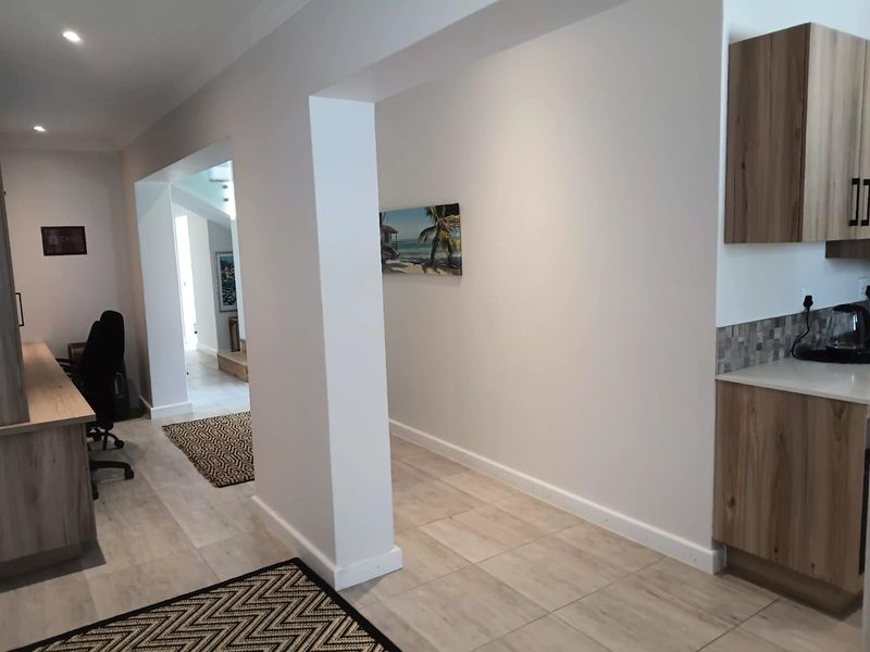 An open-plan office space featuring modern wood-finish cabinetry, neutral tiled flooring, and recessed lighting, creating a clean and professional work environment.