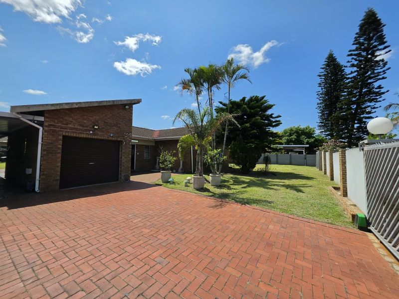 Front view of the property featuring a brick facade, paved driveway, and a secure gated entrance with a well-maintained lawn area.