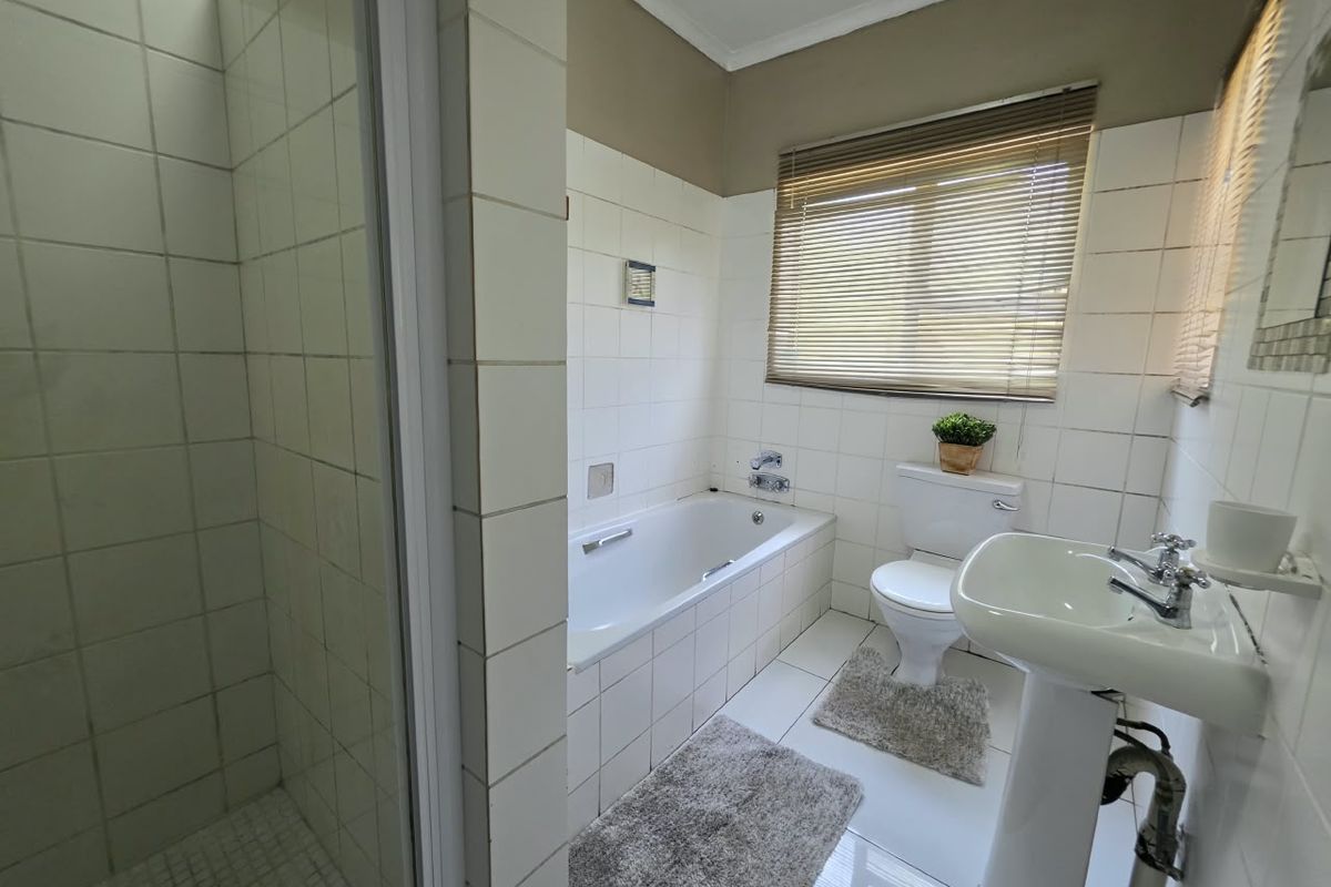 A functional bathroom featuring a separate shower enclosure, built-in bathtub, pedestal basin, and toilet with tiled finishes throughout.