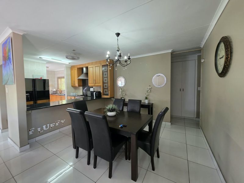 Open-plan dining area flowing into a functional kitchen with granite countertops, wooden cabinetry, and tiled flooring throughout.
