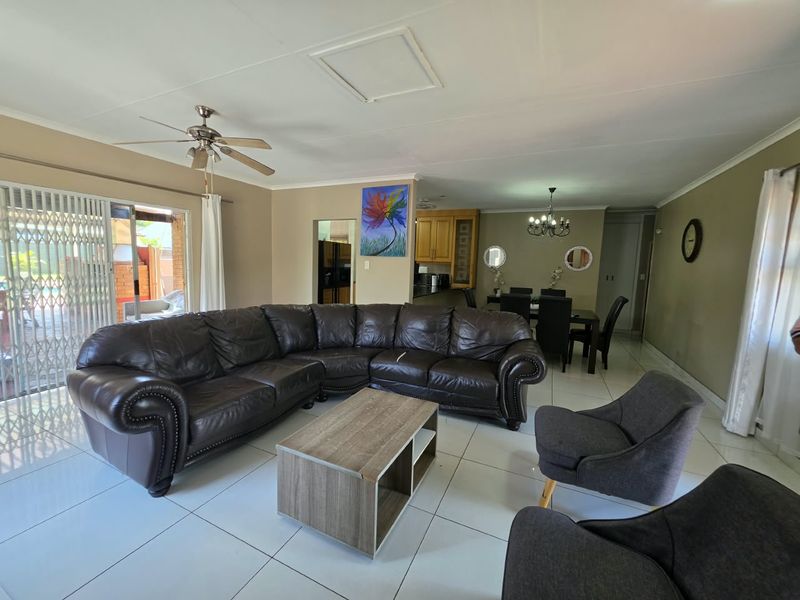 Spacious open-plan living and dining area featuring tiled flooring, a ceiling fan, and direct access to an outdoor patio through sliding glass doors.
