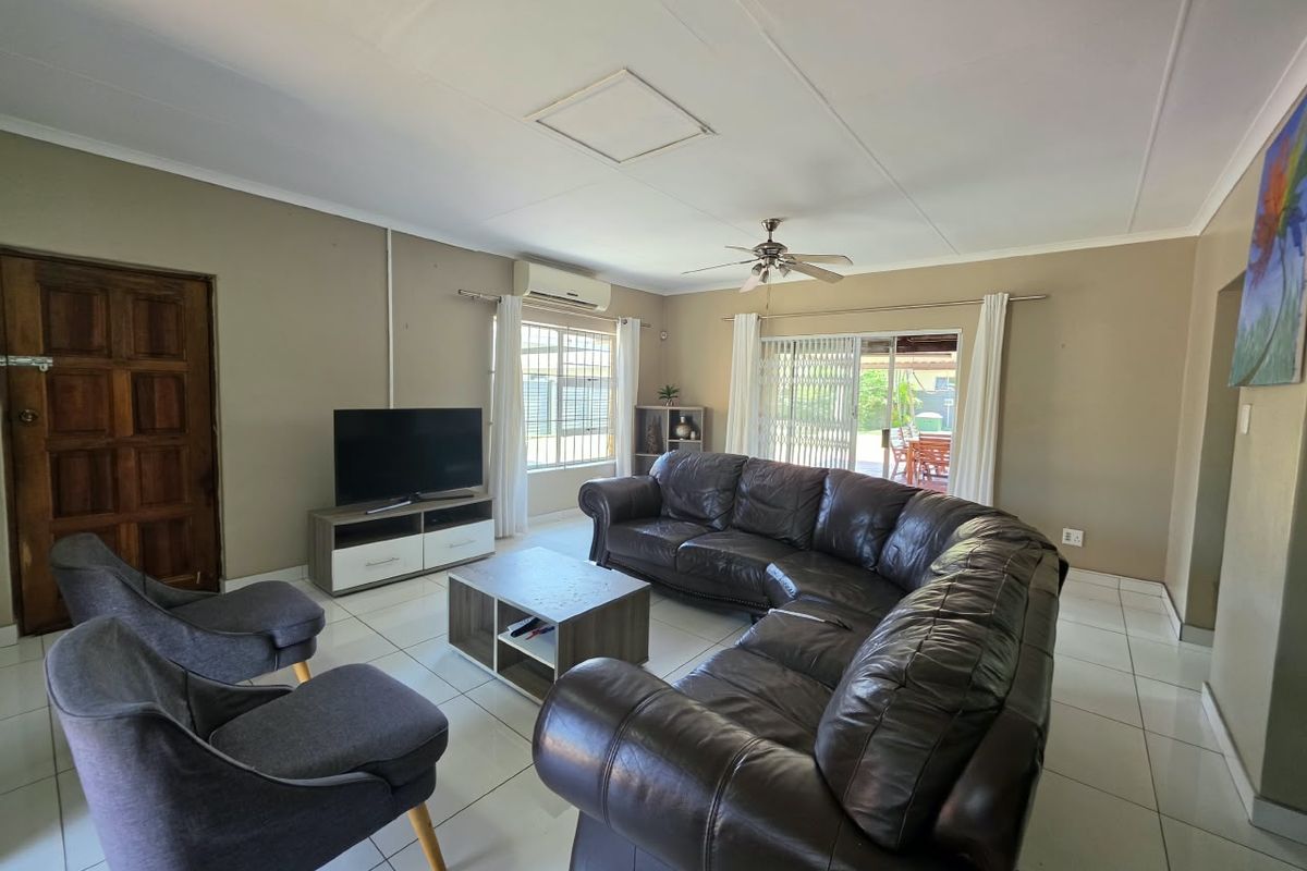 Spacious living room featuring tiled flooring, a ceiling fan, split-system air conditioning, and direct access to the outdoor patio area through sliding glass doors.