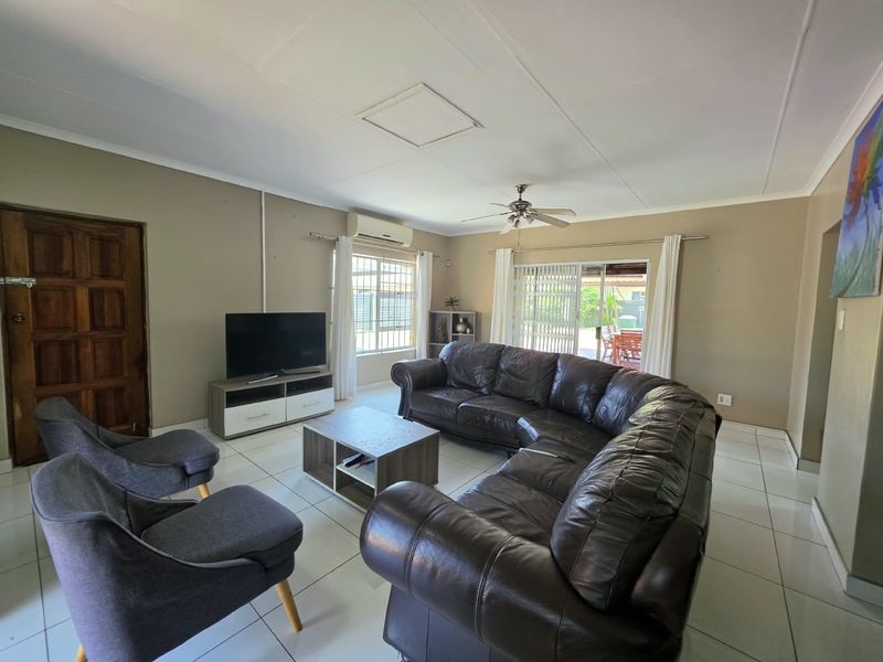 Spacious living room featuring tiled flooring, a ceiling fan, split-system air conditioning, and direct access to the outdoor patio area through sliding glass doors.
