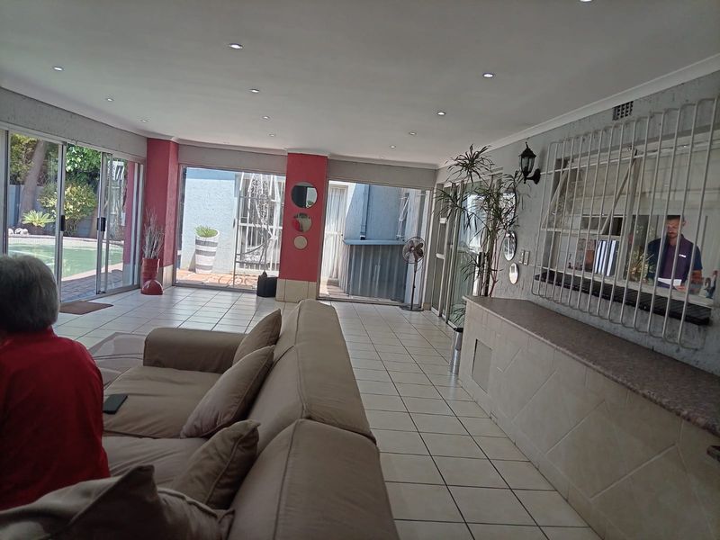 Spacious open-plan living area featuring tiled flooring, recessed lighting, and a built-in serving counter with direct access to the outdoor pool area.