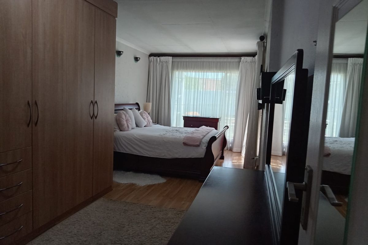 A bedroom featuring laminate flooring, a large built-in wardrobe, and a sliding door providing natural light.