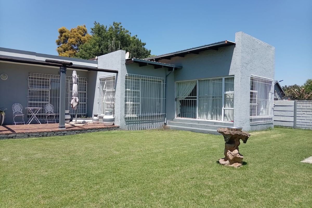 Rear view of the property featuring a tiled patio area, sliding glass doors with security bars, and a well-maintained lawn.