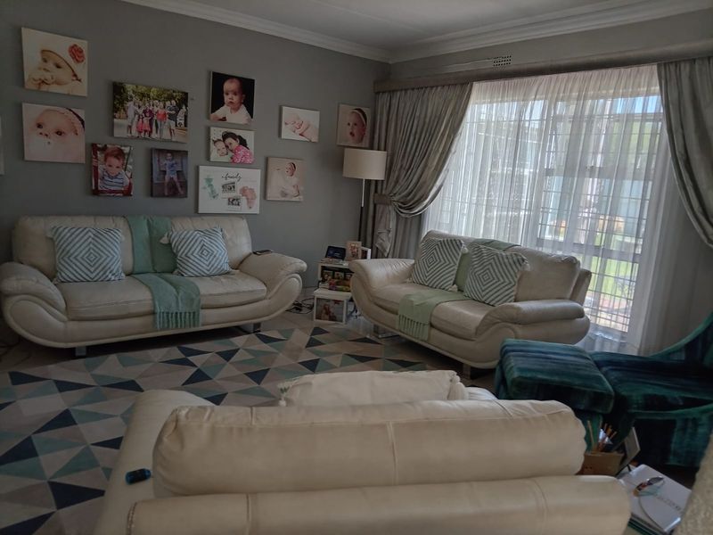 A comfortable living room featuring neutral wall tones, large windows with elegant drapes, and classic coving detail, creating a warm and inviting atmosphere.