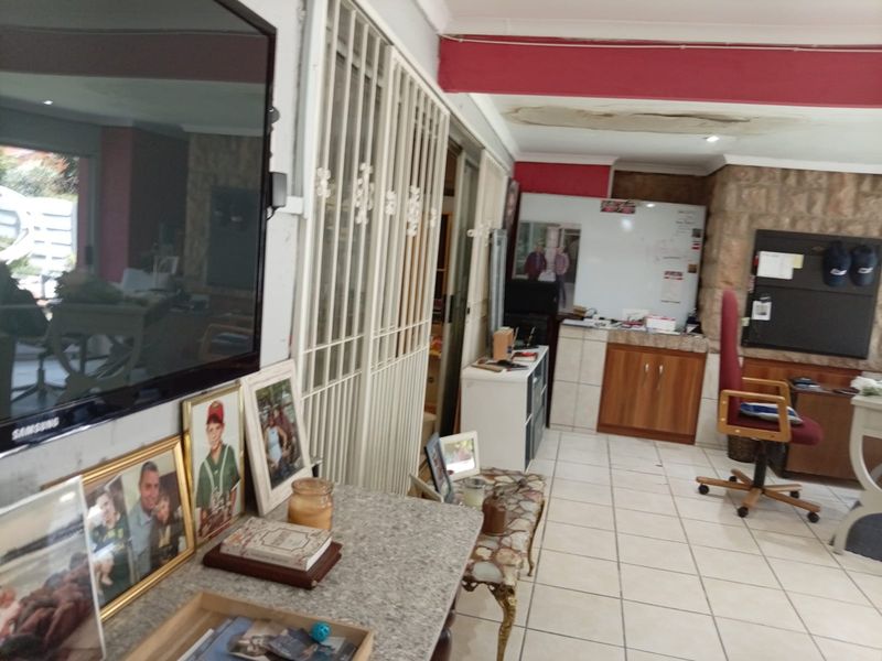 Living area featuring tiled flooring, a stone feature wall, and security gates, currently showing signs of ceiling water damage.