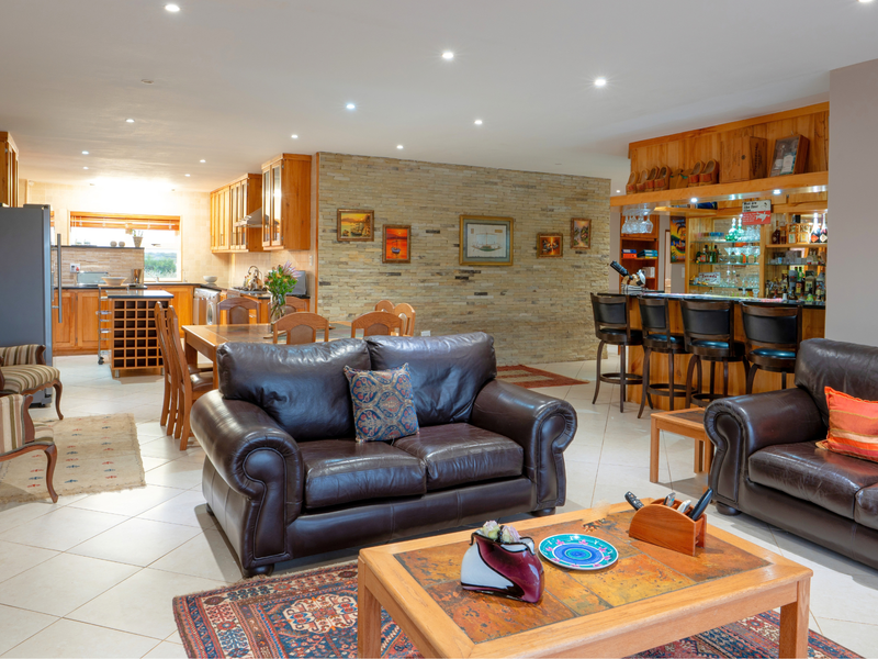 Spacious open-plan living area featuring a stone accent wall, integrated bar, and a functional kitchen with ample cabinetry and island workspace.