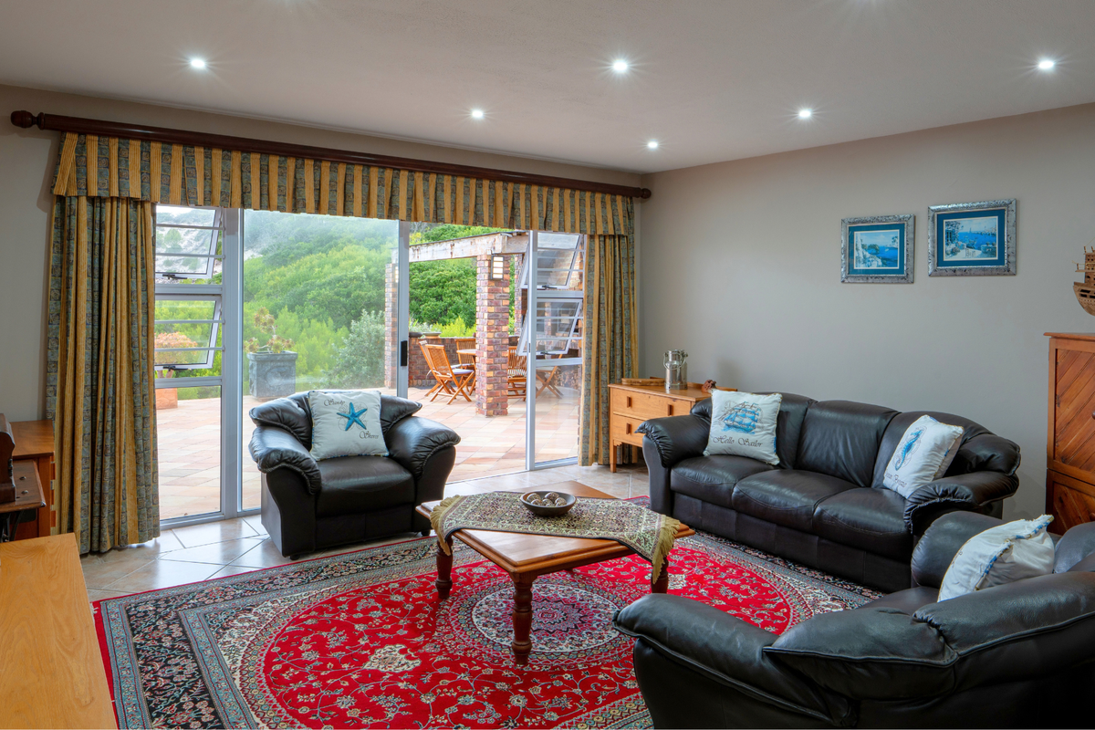 A well-lit living room featuring recessed downlights, tiled flooring, and large sliding glass doors that provide direct access to an outdoor patio area.