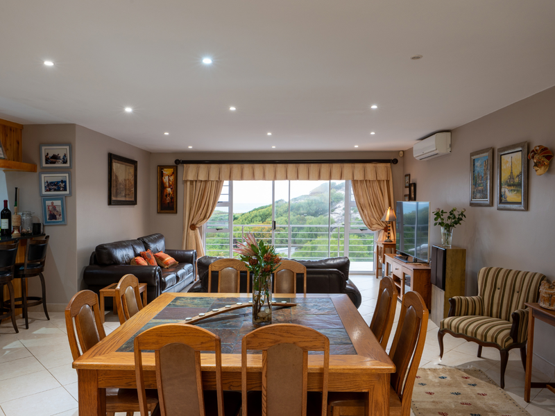 Spacious open-plan living and dining area featuring tiled floors, a built-in bar, and large sliding doors leading to an outdoor view.