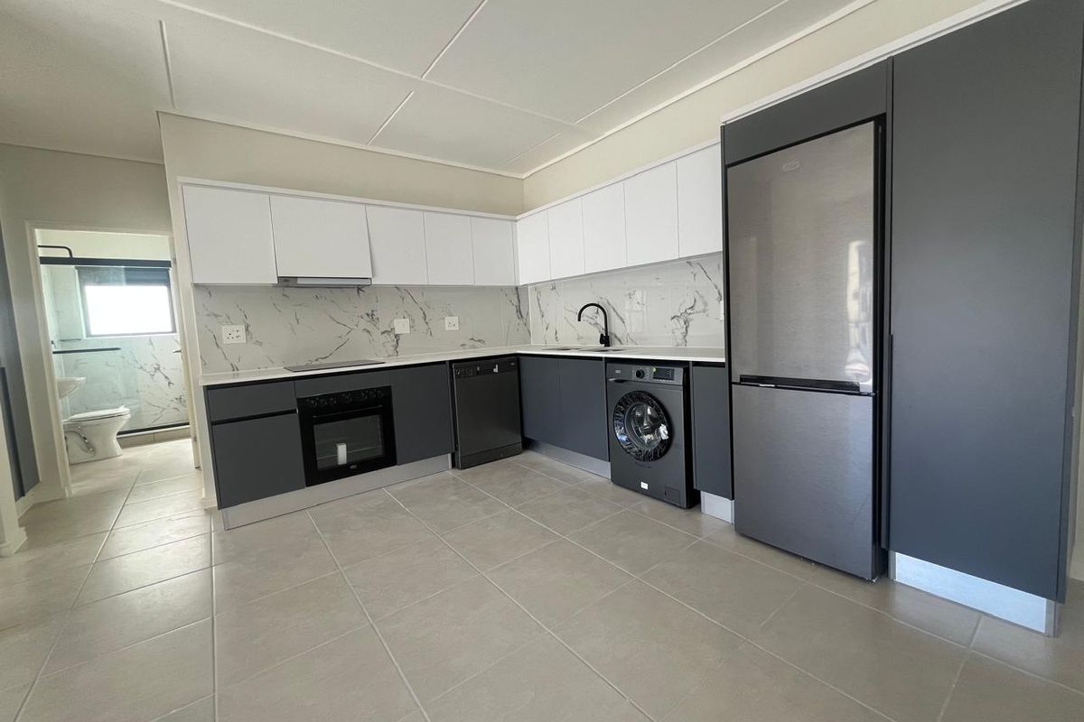 Modern kitchen featuring sleek two-tone cabinetry, marble-look splashback, integrated appliances, and tiled flooring, with an adjacent view into the bathroom.