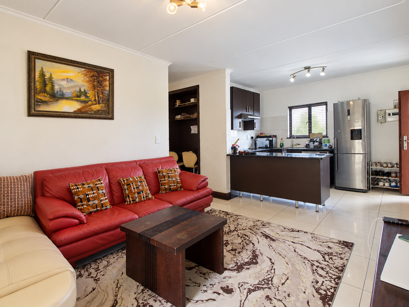 An open-plan living and kitchen area featuring tiled flooring, dark wood cabinetry, and a functional kitchen island layout.