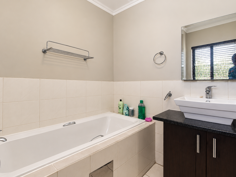 A clean, functional bathroom featuring a built-in bathtub, a modern vanity with a countertop basin, and a wall-mounted mirror.