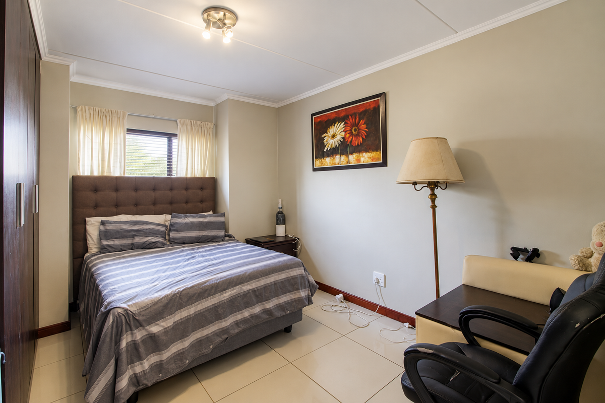 A well-maintained bedroom featuring tiled flooring, a built-in wardrobe, and neutral wall finishes, providing a clean and functional living space.