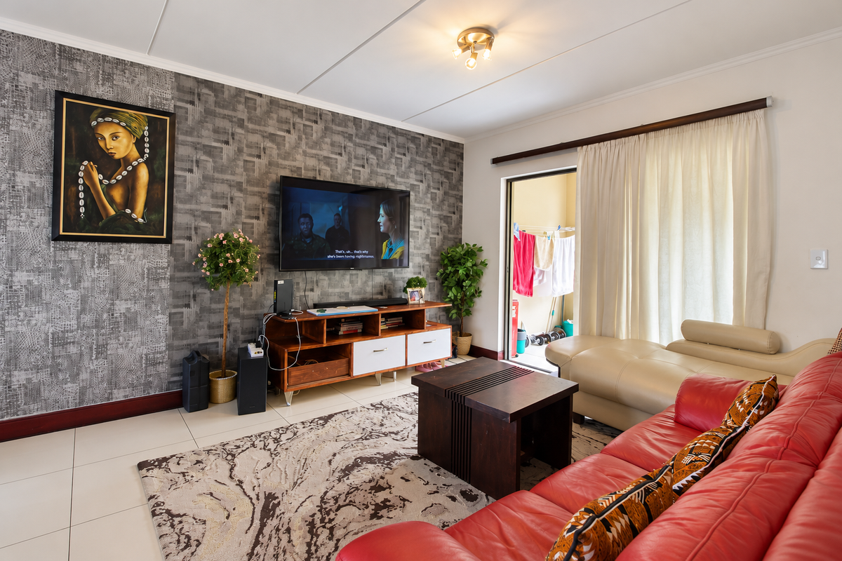 A well-maintained living room featuring a textured accent wall, tiled flooring, and direct access to an outdoor balcony area.