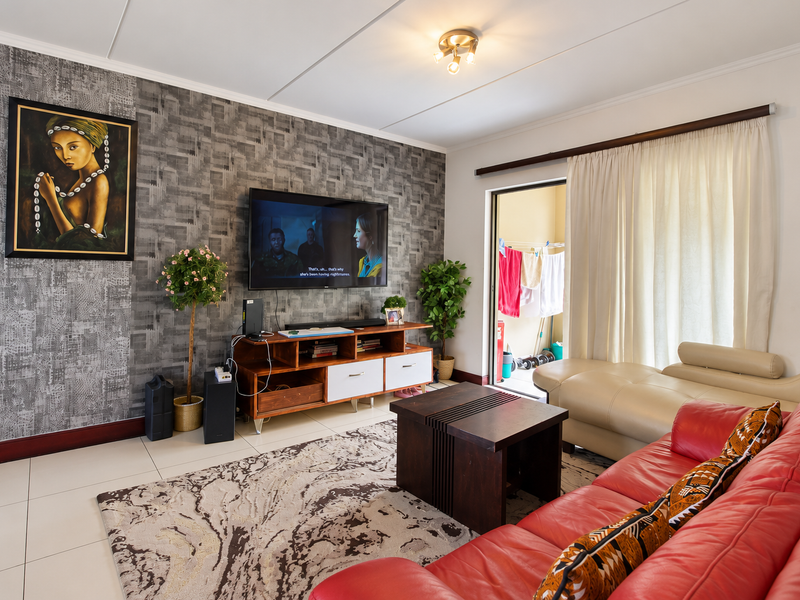A well-maintained living room featuring a textured accent wall, tiled flooring, and direct access to an outdoor balcony area.
