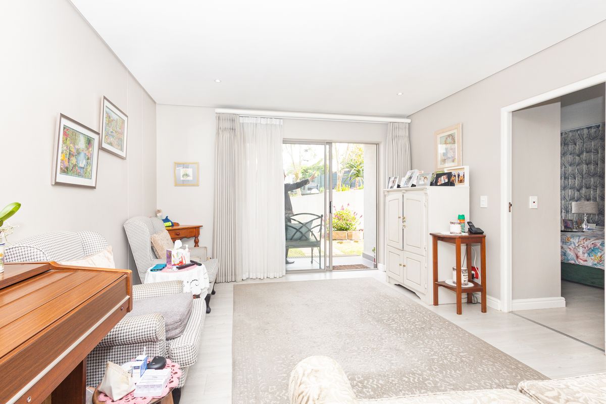 A bright living room featuring laminate flooring, recessed lighting, and a sliding glass door providing direct access to the outdoor patio area.
