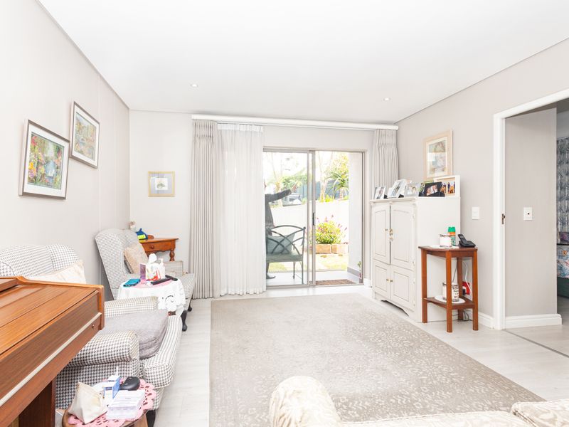 A bright living room featuring laminate flooring, recessed lighting, and a sliding glass door providing direct access to the outdoor patio area.