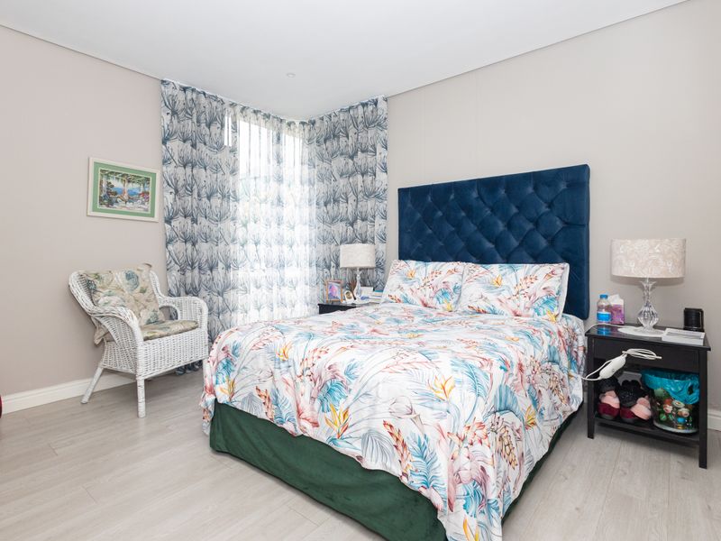A well-maintained bedroom featuring light-toned laminate flooring and neutral wall finishes, providing a clean and comfortable living space.