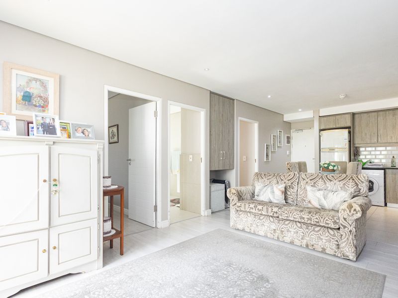 An open-plan living area featuring a modern kitchen with built-in cabinetry, subway tile backsplash, and recessed lighting, seamlessly connected to the main living space.