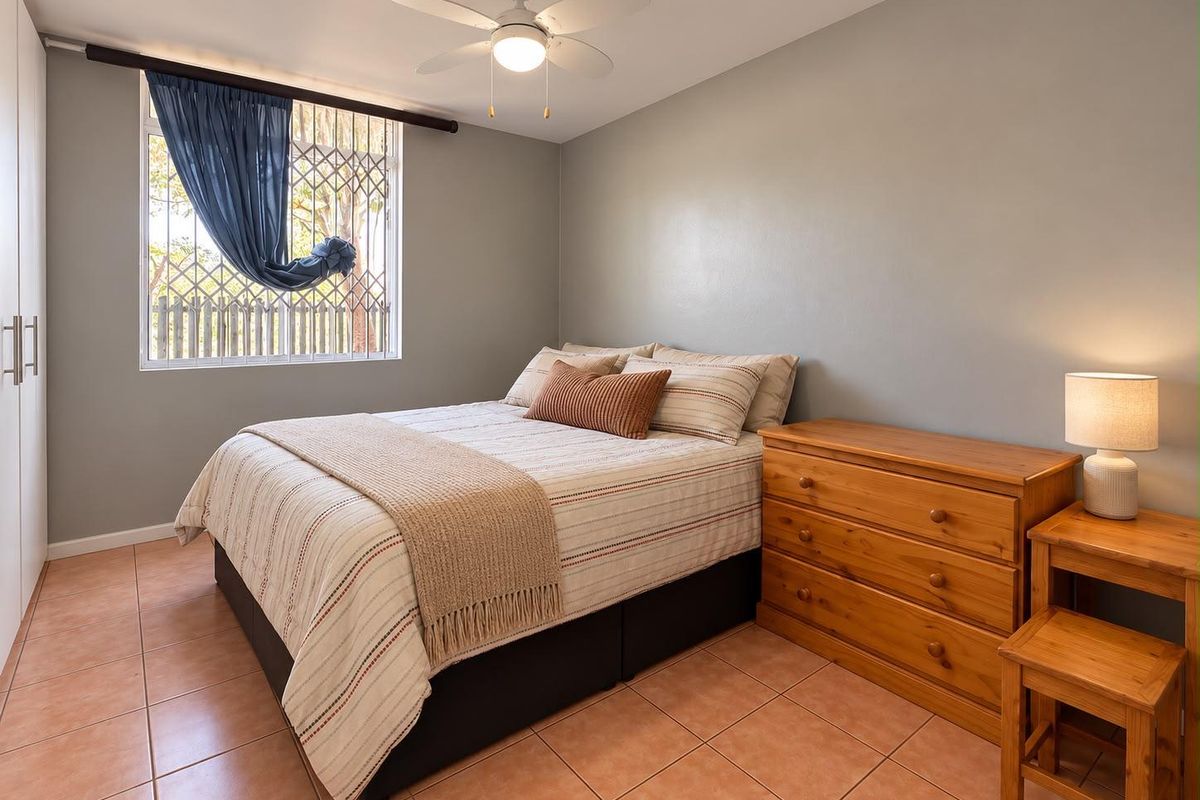 A well-maintained bedroom featuring tiled flooring, a ceiling fan, and a built-in wardrobe with a security gate on the window.