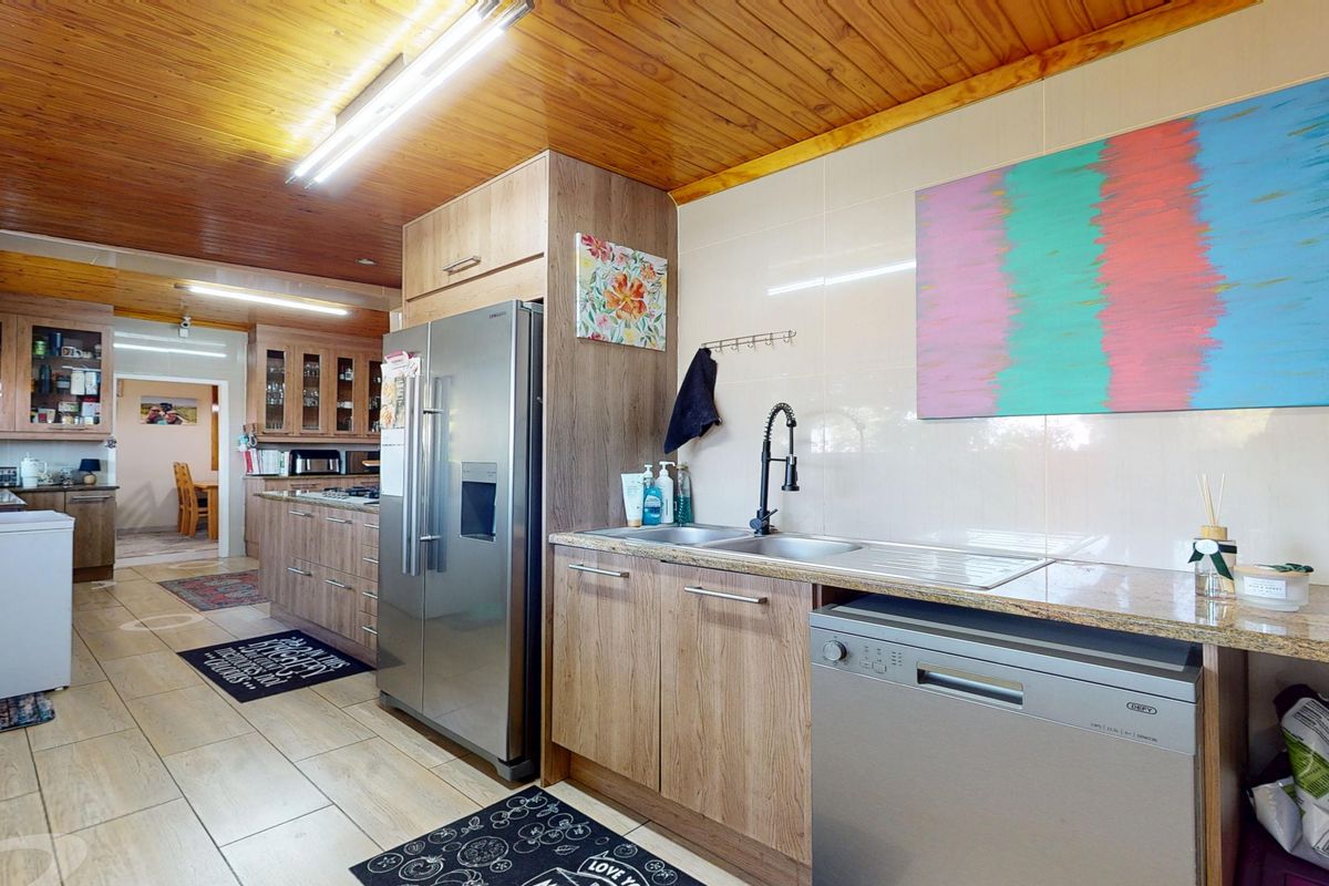A functional kitchen featuring wooden ceilings, laminate cabinetry, granite countertops, and a double sink with a modern gooseneck faucet.