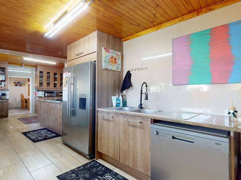A functional kitchen featuring wooden ceilings, laminate cabinetry, granite countertops, and a double sink with a modern gooseneck faucet.