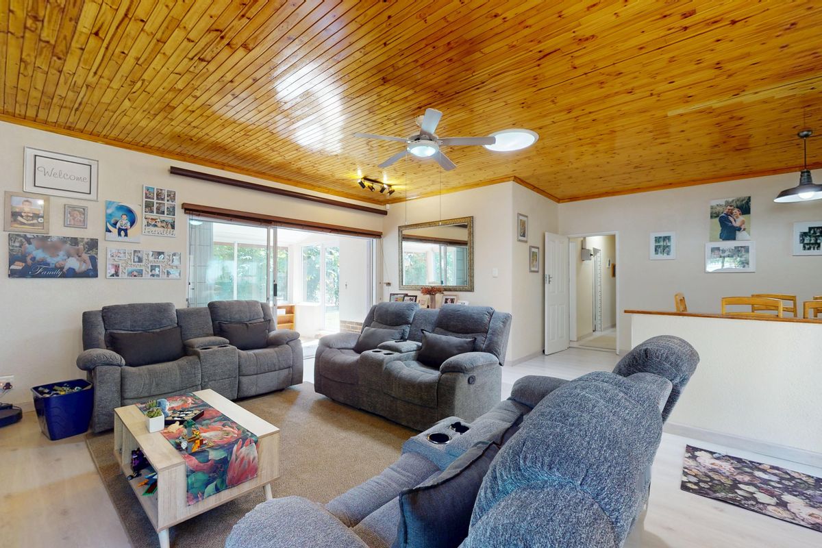 Spacious living room featuring a warm timber tongue and groove ceiling, ceiling fan, and large sliding glass doors providing access to the outdoor area.