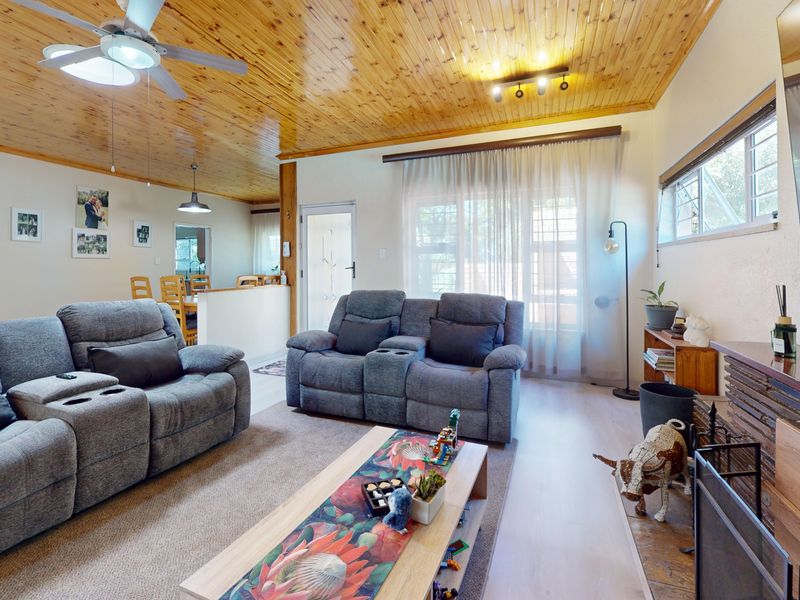 Open plan living area featuring a warm timber ceiling, fireplace, and laminate flooring, creating a comfortable and inviting space for family relaxation.