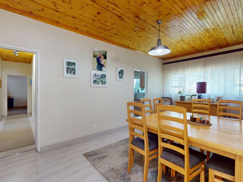 Dining room featuring a warm timber tongue and groove ceiling, laminate flooring, and a central pendant light fixture.