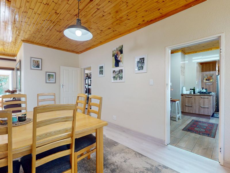 Dining area featuring a warm timber tongue and groove ceiling, laminate flooring, and direct access to the adjacent kitchen.