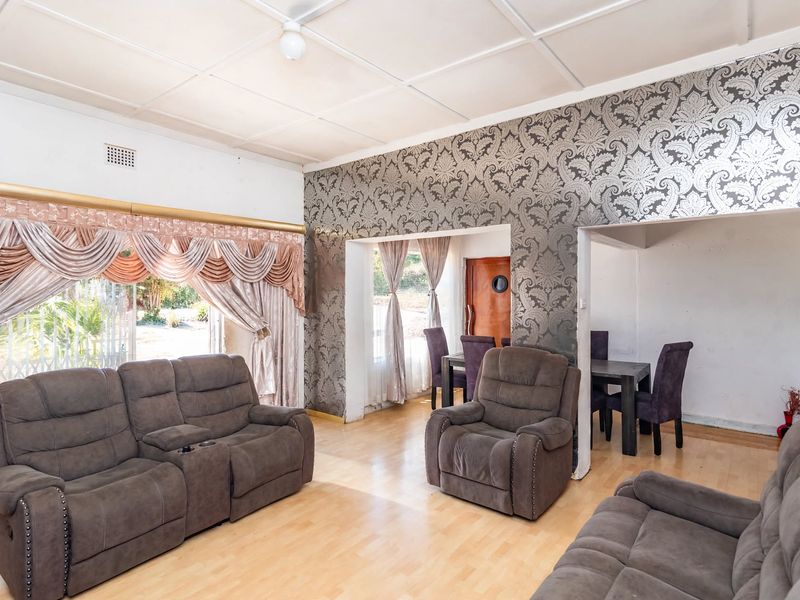 Spacious living area featuring laminate flooring, decorative wallpaper accents, and a sliding glass door providing access to the exterior.