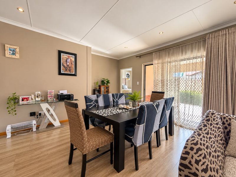 A well-lit dining area featuring laminate flooring, recessed ceiling lighting, and a large sliding glass door providing access to the outdoor patio.