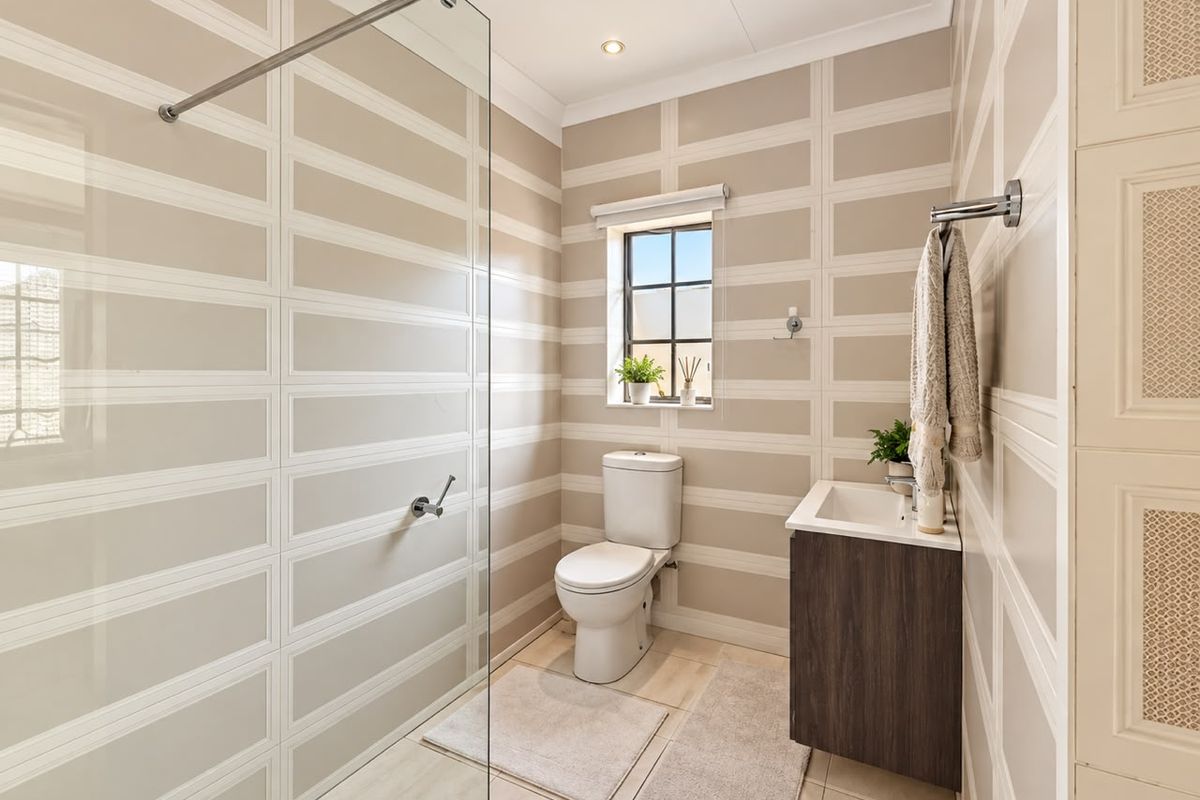 Modern bathroom featuring a glass-enclosed shower, wall-mounted vanity, and contemporary tiled walls with a neutral color palette.