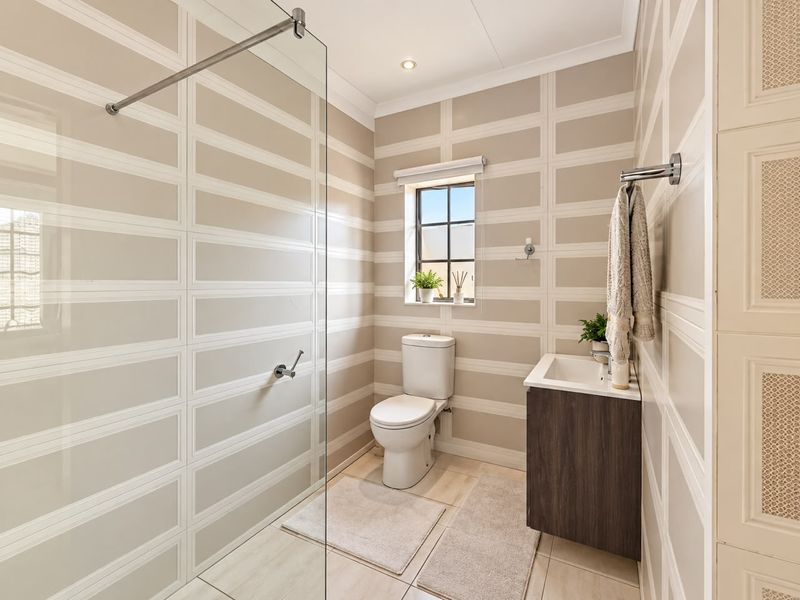 Modern bathroom featuring a glass-enclosed shower, wall-mounted vanity, and contemporary tiled walls with a neutral color palette.