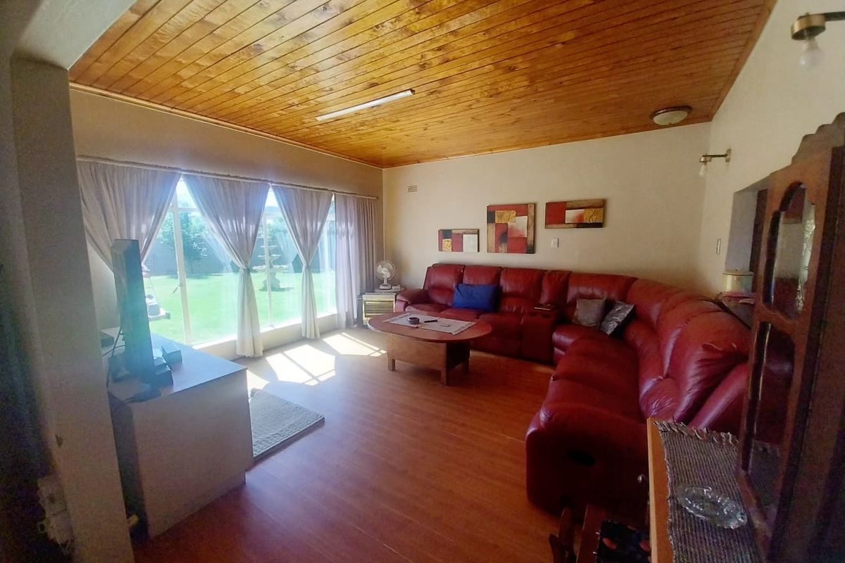 Spacious living room featuring warm timber tongue and groove ceilings, laminate flooring, and large sliding glass doors providing direct access to the garden.