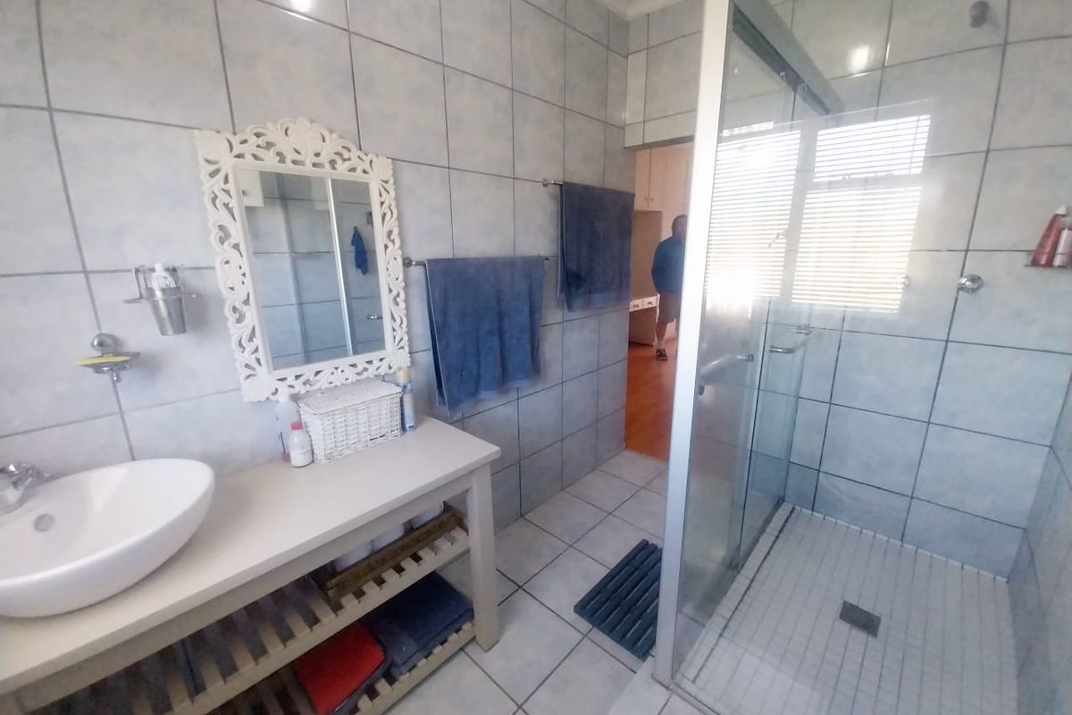 A functional bathroom featuring a walk-in shower with glass enclosure, tiled wall and floor finishes, and a vanity basin.