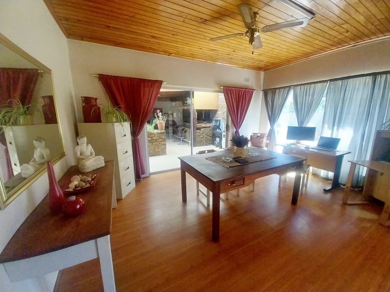 Spacious living area featuring warm timber ceilings, ceiling fan, and large sliding glass doors providing seamless access to the outdoor patio area.