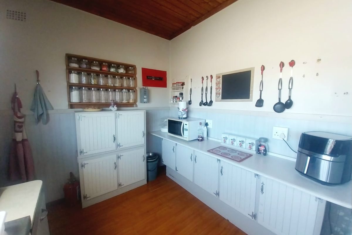 A functional kitchen area featuring white built-in cabinetry, laminate countertops, and a timber-clad ceiling, providing ample storage and workspace.