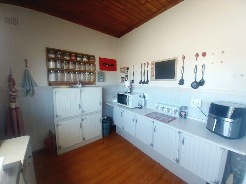 A functional kitchen area featuring white built-in cabinetry, laminate countertops, and a timber-clad ceiling, providing ample storage and workspace.