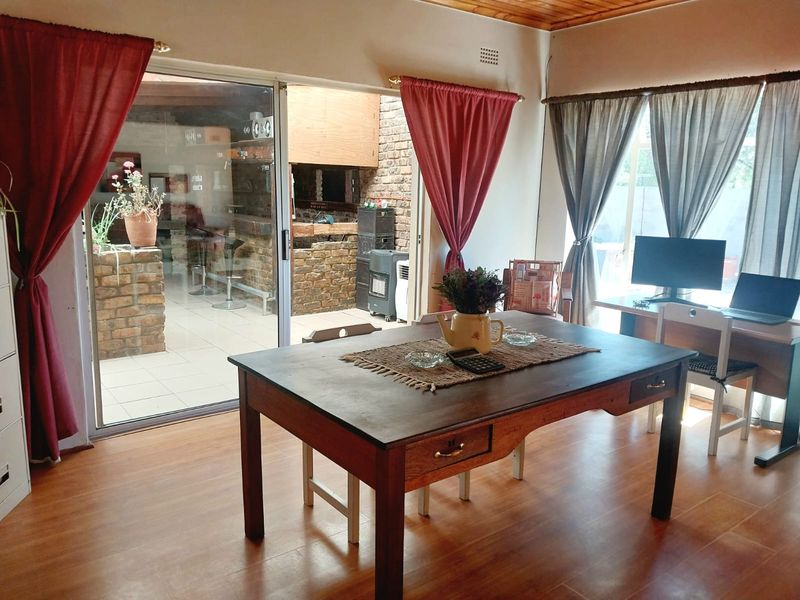 Living area featuring laminate flooring, timber ceiling, and sliding glass doors opening to an outdoor patio with a built-in brick braai.