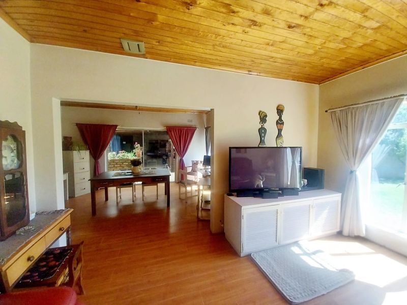Open plan living and dining area featuring warm timber ceilings, laminate flooring, and large sliding glass doors providing access to the outdoor space.