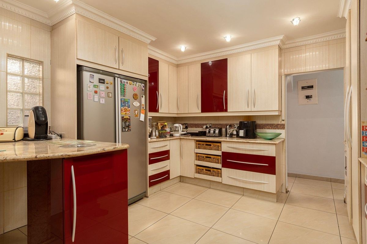 A well-maintained kitchen featuring two-tone cabinetry, granite countertops, tiled flooring, and recessed lighting, offering a functional and organized culinary space.