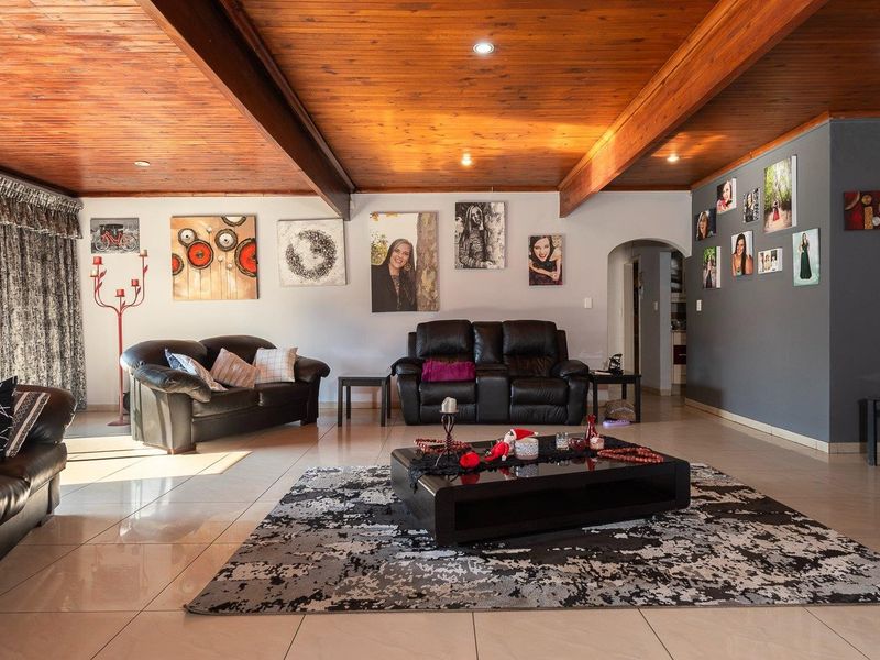 Spacious living room featuring a warm timber-clad ceiling with exposed beams, recessed lighting, and neutral tiled flooring, creating a comfortable and inviting atmosphere.