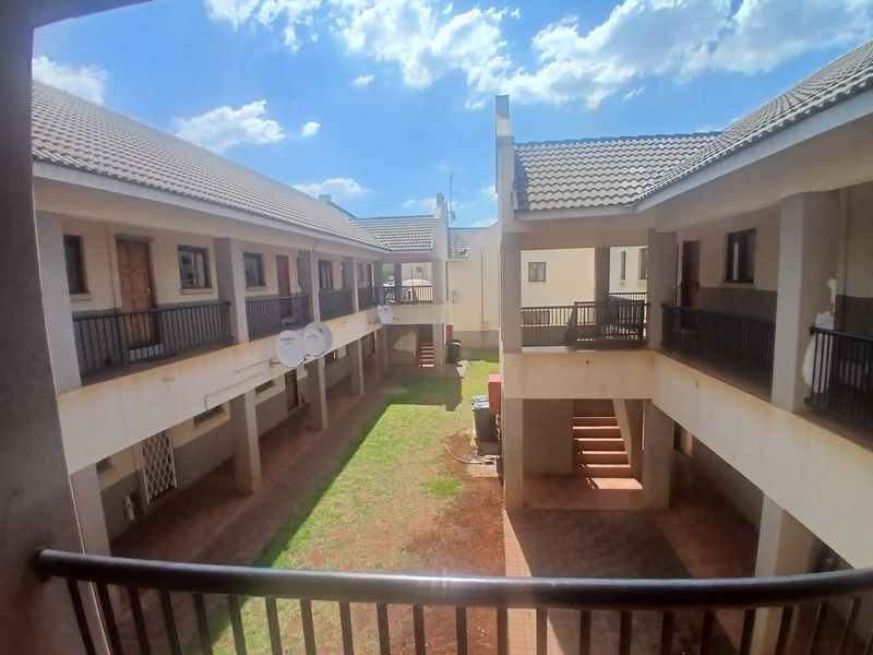 View of the apartment complex courtyard featuring paved walkways, communal garden space, and multi-level balcony access.