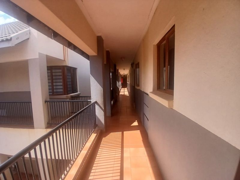 An exterior apartment hallway featuring tiled flooring and metal balustrades, providing access to residential units.